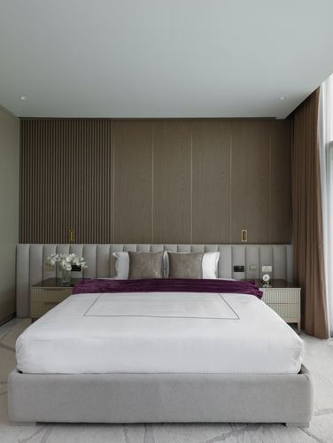 Neutral bedroom with wood panel wall, channel-tufted headboard and a purple velvet throw