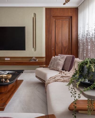 Living room with walnut door, floating tv console, marble floor, and cushioned sofa with sheer curtains