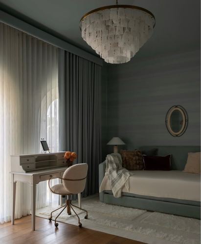 Sage green bedroom corner with daybed, desk, arched sheer-curtained window and capiz chandelier