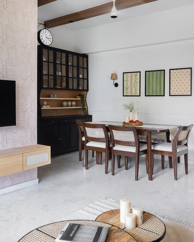 Dining room with cane chairs, wood table, black display cabinet and framed botanical prints