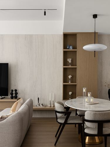 Living-dining space with stone wall, wood shelving, marble table and disc pendant light