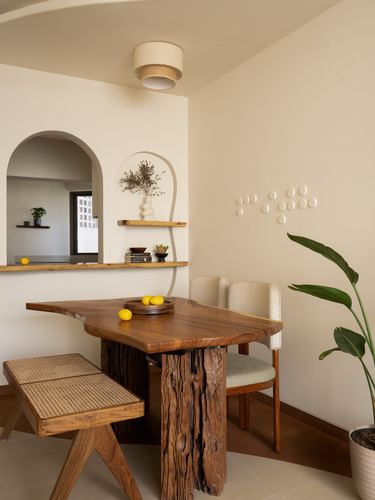 Dining nook with live-edge wood table, cane bench, arched pass-through and ceramic wall art