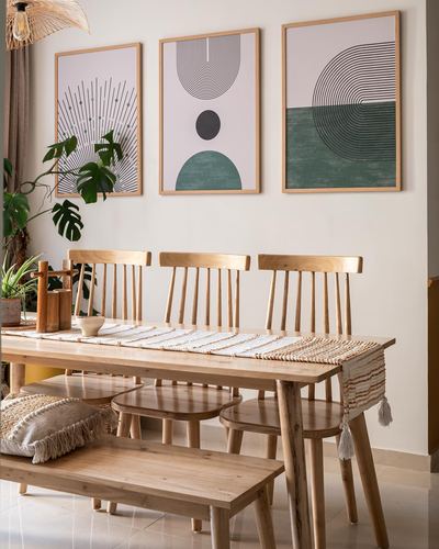 Wooden dining table with spindle chairs beneath three framed abstract prints on a cream wall