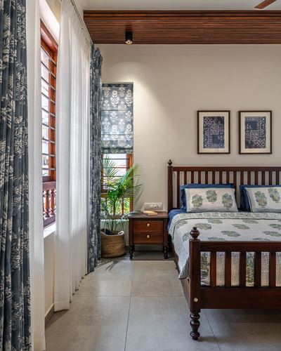 Traditional wooden four-poster bed with blue block-print linens beside shuttered window