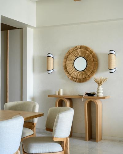 Dining room with arched wooden console, sunburst mirror, cane sconces and linen chairs