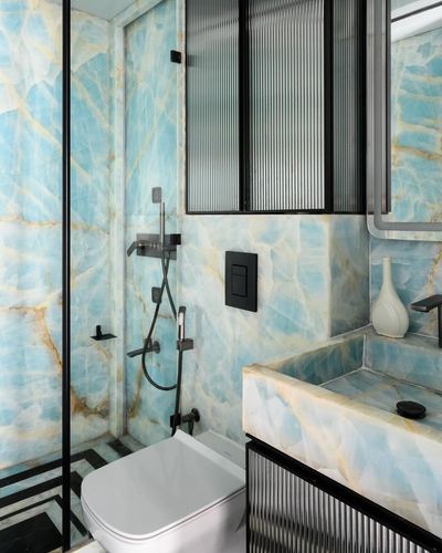 Bathroom with turquoise-veined stone walls, black fixtures, and fluted glass shower partition