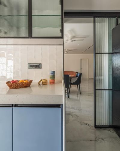 Kitchen counter with fruit basket beside sliding glass door opening to marble-floored dining area