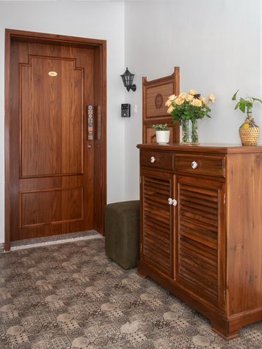Wooden entry door beside a louvered wood cabinet with flowers, patterned tile floor