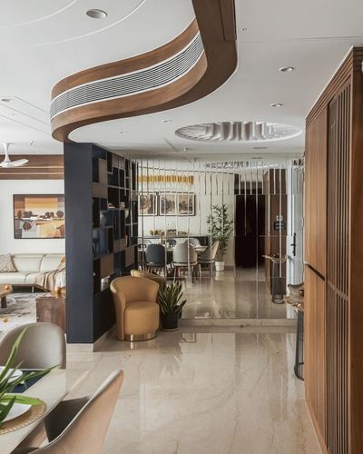 Open-plan living and dining area with sculptural wood ceiling, fluted mirror partition, marble floor and navy bookshelf