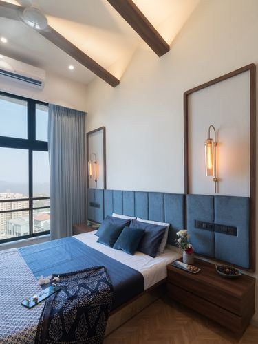 Bedroom with blue velvet headboard panels, wood beams, brass sconces and city skyline view