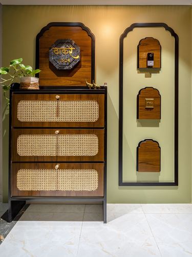 Entryway with cane-front wooden cabinet and arched wall niches on olive green wall in Pune apartment