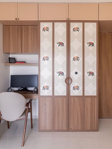 Study nook beside a wardrobe with elephant-print panelled doors and wood cabinetry