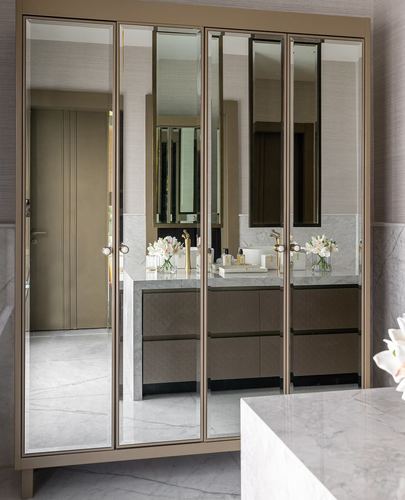Mirrored wardrobe reflecting marble vanity with gold fixtures in luxury bathroom