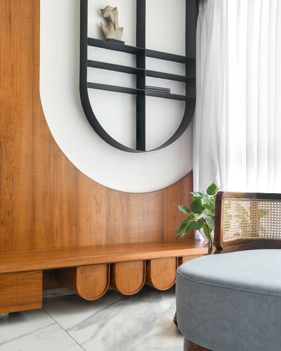 Wooden wall niche with black geometric shelf, bench seat, cane chair, marble floor