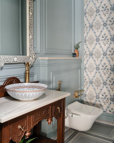Powder room with carved wood vanity, patterned basin, inlay mirror, and floral wallpaper accent wall