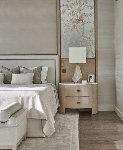 Neutral master bedroom with curved wood nightstand, marble top, and floral panel beside upholstered bed