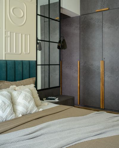 Bedroom corner with teal channel-tufted headboard, mirrored wall, and grey textured wardrobe with wood handles