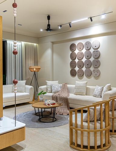 Living room with cream sofas, round wood table, and a wall grid of sculpted face discs