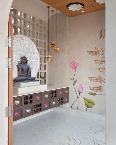 Pooja room with jali-backed buddha statue, brass lotus pendants, and painted lotus mural on wall