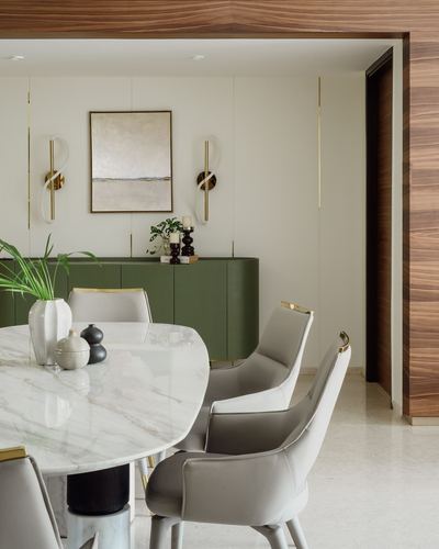 Dining area with marble table, cream leather chairs, green sideboard and brass sconces under a wood-clad archway