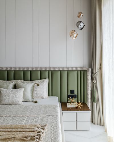 Bedroom corner with fluted sage green headboard, geode pendant lights, and white nightstand