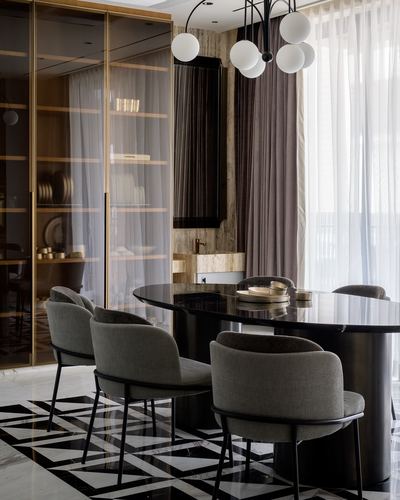 Dining room with oval black table, grey chairs, globe chandelier, and geometric marble floor
