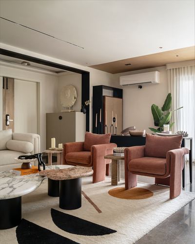 Living room with terracotta velvet chairs, round marble coffee table, and patterned rug