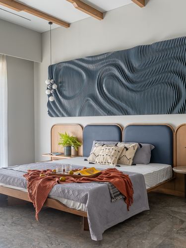 Bedroom with arched wood headboard, blue upholstery, and wavy striped wall art above bed