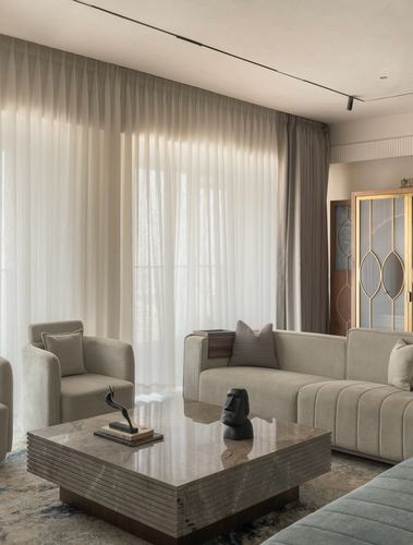 Beige living room with sheer curtains, channel-tufted sofa, and marble coffee table
