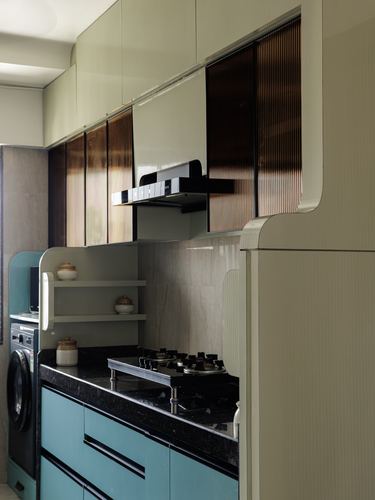Sage green kitchen with fluted glass cabinets, teal drawers, and dark stone countertop with gas stove