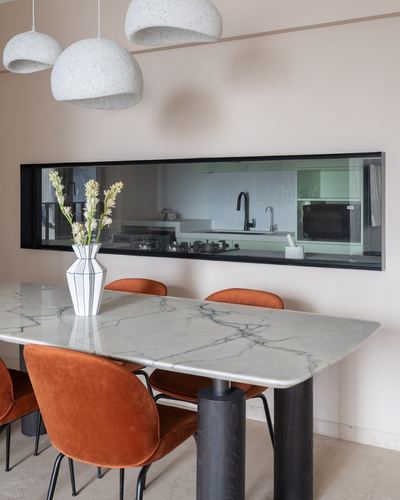 Dining table with marble-look top and terracotta velvet chairs beneath textured pendant lights