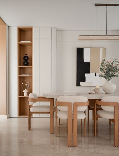 Minimalist dining nook with wood chairs, stone table, abstract art, and built-in shelving