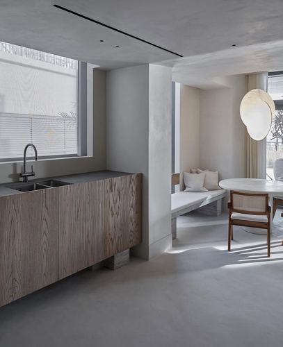 Minimalist wabi-sabi kitchen and dining nook with wood cabinetry, plaster walls, and soft daylight