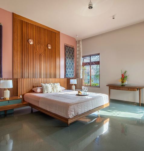 Bedroom with fluted wood headboard wall, floating bed, pink walls, and terrazzo floor lit by side window