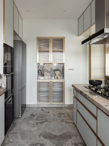 Galley kitchen with fluted glass cabinets, brass trim, stone counters and stone flooring