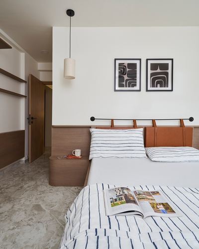 Bedroom with tan leather hanging headboard, striped linens, cylindrical pendant light and graphic wall art