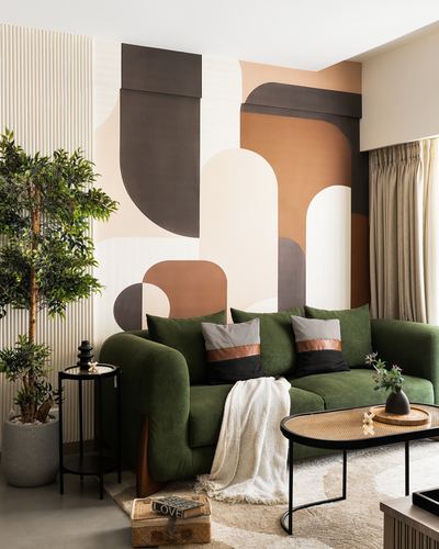 Living room with green velvet sofa against a terracotta and brown geometric arch mural wall