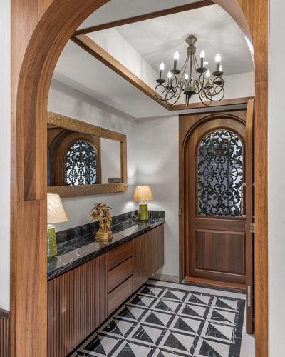 Foyer with arched wood door, iron grille, chandelier, and geometric marble floor