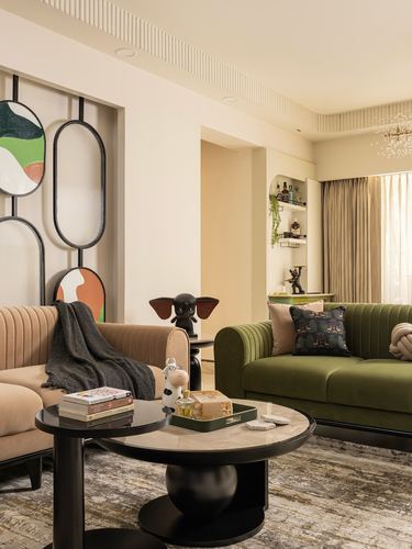 Living room with olive green and beige sofas facing a round marble coffee table and sculptural wall panel