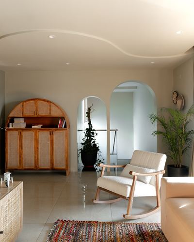 Living room with arched cane cabinet, rocking chair, and layered archways leading inward