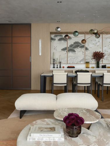 Cream bench and marble tables in foreground with dining table and sculptural pendant lights beyond