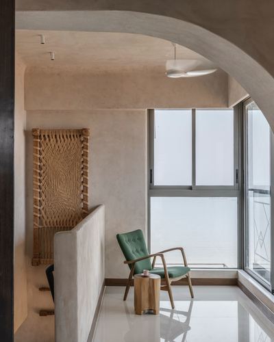 Green armchair by window nook beneath sculpted plaster arch with woven cane panel