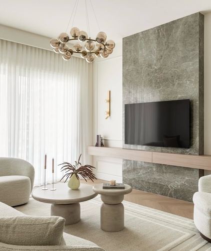 Living room with grey marble feature wall, mounted tv, boucle armchairs and sheer drapery
