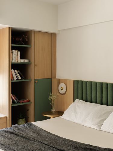 Bedroom corner with fluted green headboard, wood wardrobe with open bookshelf and brass side table