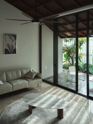 Living room with marble table and leather sofa opening through glass wall to a green courtyard