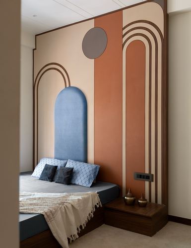 Bedroom with terracotta and beige geometric mural wall and blue arched upholstered headboard