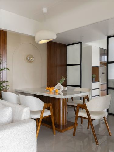 Dining nook with marble table, fluted wood base, boucle chairs and arched wall niche