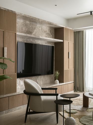 Living room TV wall in stone with fluted wood cabinets, cream chair and round side tables