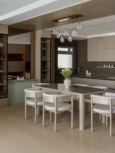 Dining area with oval table, cream boucle chairs, and layered pendant lights above