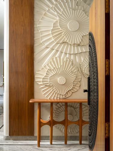 Entry foyer with sculptural floral relief wall panel, wooden console, and carved dark door